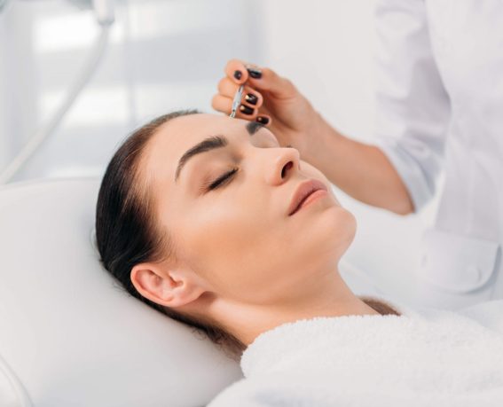 Beautiful woman receiving facial cleansing in spa center